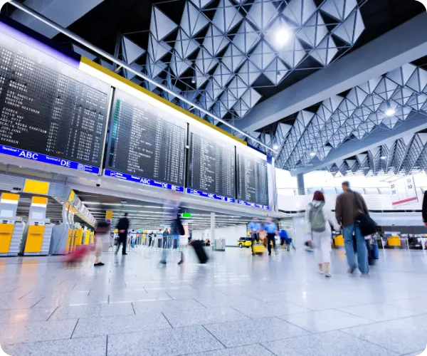 Terminal de aeroporto com passageiros caminhando sob os painéis de voos e um teto com design geométrico
